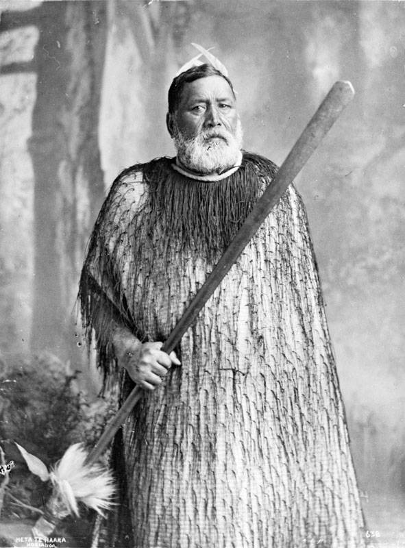 Heta Te Haara dressed in a cloak holding a taiaha